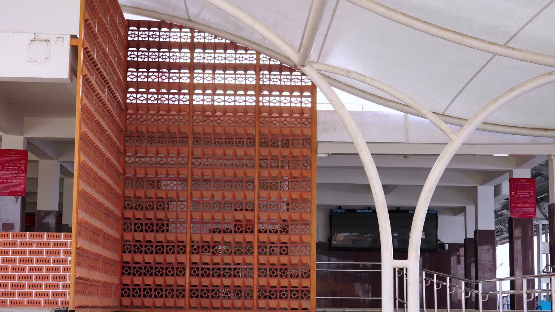 Terracotta jali wall under the white canopy arches